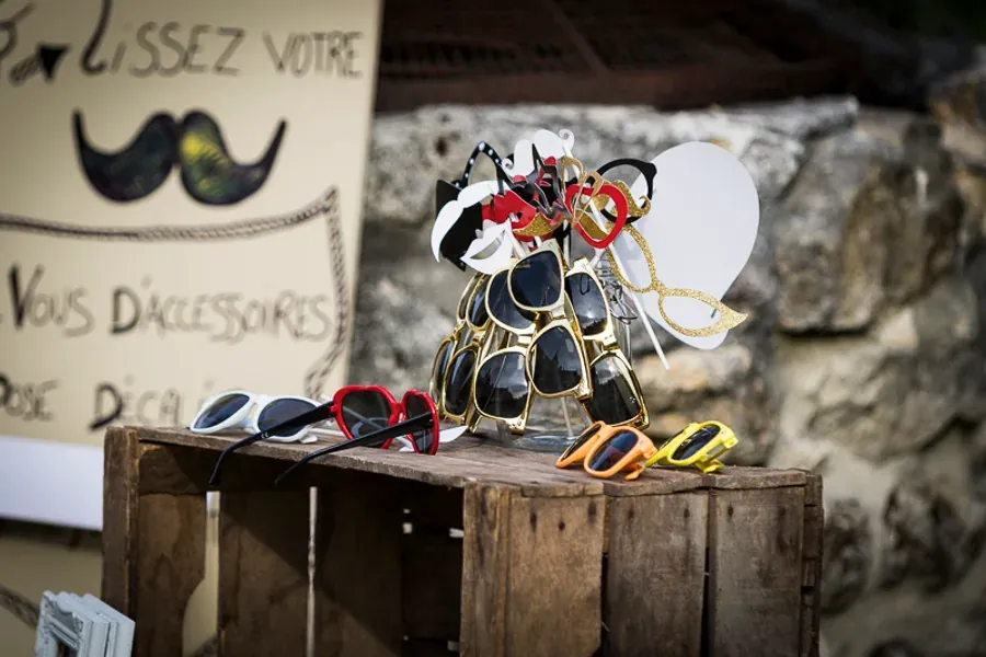 Accessoires de photobooth posés sur une caisse en bois : lunettes, moustaches, cadres