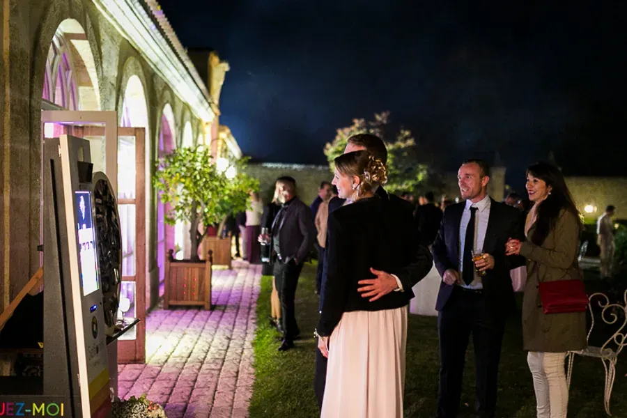 Borne photo installée dans l'allée d'un domaine de réception, invités en soirée